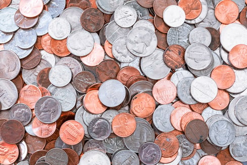 United States pennies, nickels, dimes, and quarters spread out in pile.  